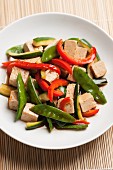 Stir-fried tofu cubes and vegetables (mange tout, courgette and red peppers) with soy sauce