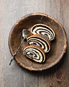 Three slices of poppyseed strudel in a wooden dish