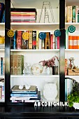 Bookcase decorated with garland and various vases next to books
