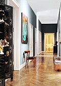 Golden, illuminated door at end of long hallway in Viennese period apartment; Chinese screen in foreground to one side