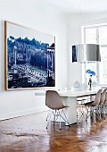 Designer dining area with long table, classic chairs, cylindrical lampshade and large photo of Roman Forum