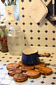 Trivet made from discs of wood on kitchen counter tiled in vintage pattern