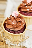 Schokoladencupcake mit Zuckerperlen und Zuckerrose
