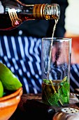 A mojito being made (brown rum being added)