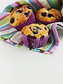 Three blueberry muffins in a stripped cloth