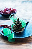 Fir cones and green ribbon used as menu on blue plate