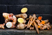 Fresh galangal, fingerroots, turmeric and ginger on a wooden board