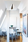 Tall dining counter and bar stools in converted attic with contemporary ceiling light in foreground