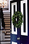 Open blue and white front door decorated with festive Christmas wreath