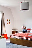 Large bed with red and white bed linen in child's bedroom