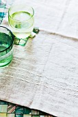Green water glasses on a beige-coloured linen cloth