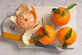 Mandarins, whole and peeled, on a chopping board