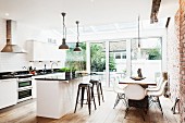 Modern, open-plan interior with exposed brickwork - dining area and kitchen in front of terrace doors