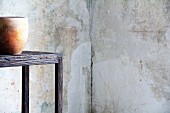 Clay pot on wooden table in corner against patinated walls