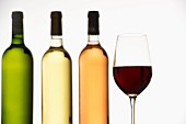 Vier verschiedene Bordeaux-Weine in Flaschen & Weinglas