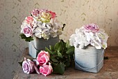Vintage ambiance with romantic arrangements of roses in small zinc buckets and roses on wooden table