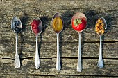 Fresh fruit and nuts on spoons depicting muesli ingredients