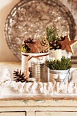 Tin cans of Christmas decorations on tray with metal dish leaning against wall in background