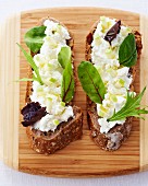 Slices of bread topped with cream cheese and herbs