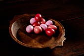 Pink and red Easter eggs in a wooden bowl