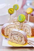 Slices of lemon Swiss roll decorated with toothpicks and bottle tops on white china plate
