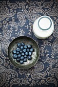 Fresh blueberries in a metal bowl with a bottle of milk
