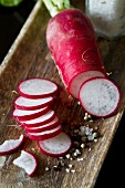 Red radishes, salt and peppercorns in a wooden dish