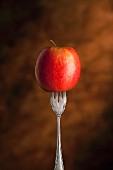 A red apple skewered on a fork