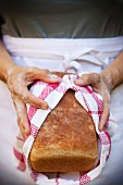 A woman holding a loaf of freshly baked bread