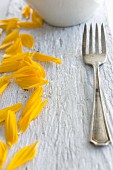 Sunflower petals and a fork on a wooden board