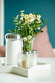 Arrangement of sugar, salt and pepper shakers and posy of chamomile on white table