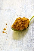 A spoonful of spice mixture made from curry and coconut flakes