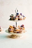 Various cupcakes decorated with flowers on a cake stand