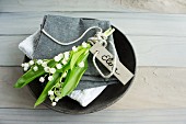 Lily of the valley and name tag on linen napkin in bowl
