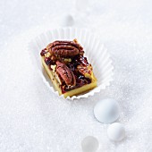 A slice of pecan and cranberry cake in a paper case