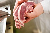 A butcher holding freshly cut lamb chops