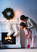 Mother and daughter next to festively decorated fireplace