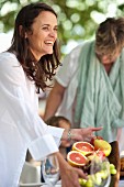 A laughing woman serving fresh fruit