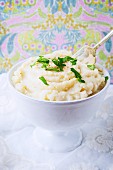 A bowl of mashed cauliflower garnished with parsley