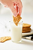 A biscuit being dipped into a glass of milk