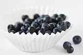 Fresh Blueberries in a Paper Muffin Cup; Blueberries Next to Cup