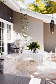 Delicate metal chairs and table on stone floor of sunny terrace adjoining wooden house