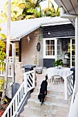 Dog on steps leading to furnished terrace of wooden house