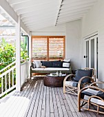 Rattan armchairs and coffee table on roofed wooden veranda adjoining house