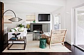 Modernes Wohnzimmer mit Couchtisch und rustikalem Sessel aus Holzlamellen vor Kamin & Fernseher