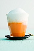 An orange and carrot smoothie topped with warm coconut foam