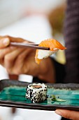 A person eating salmon sushi in a restaurant