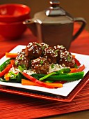 Meatballs with hoisin sauce and sesame seed on a bed of rice (Asia)