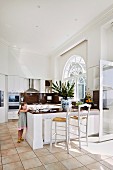 Child next to kitchen counter and barstools in open kitchen with tiled floor in Mediterranean ambiance