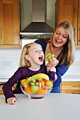 Mutter füttert Tochter mit Trauben in der Küche